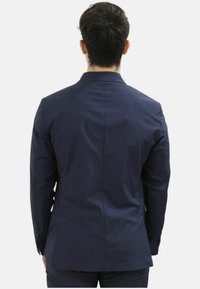 Giacca da suit blu navy con vestibilità su misura, caratterizzata da una texture liscia e uno spacco posteriore unico. Bottoni sui polsini e design con revers a punta.