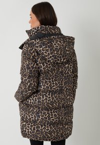 Bundička s leopardím potiskem, vysokým límcem, černými akcenty a prošívanou strukturou. Obsahuje kapuci a elastické manžety.