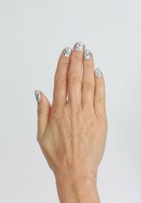 Hand mit manikürten Nägeln, die eine weiße Grundfarbe und ein schwarzes geometrisches Muster zeigen. Die Hautstruktur ist sichtbar und hat ein natürliches Aussehen.