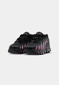 Black athletic shoes with pink accents, featuring textured mesh upper, distinct wave-like design, and a cushioned sole with visible air units.