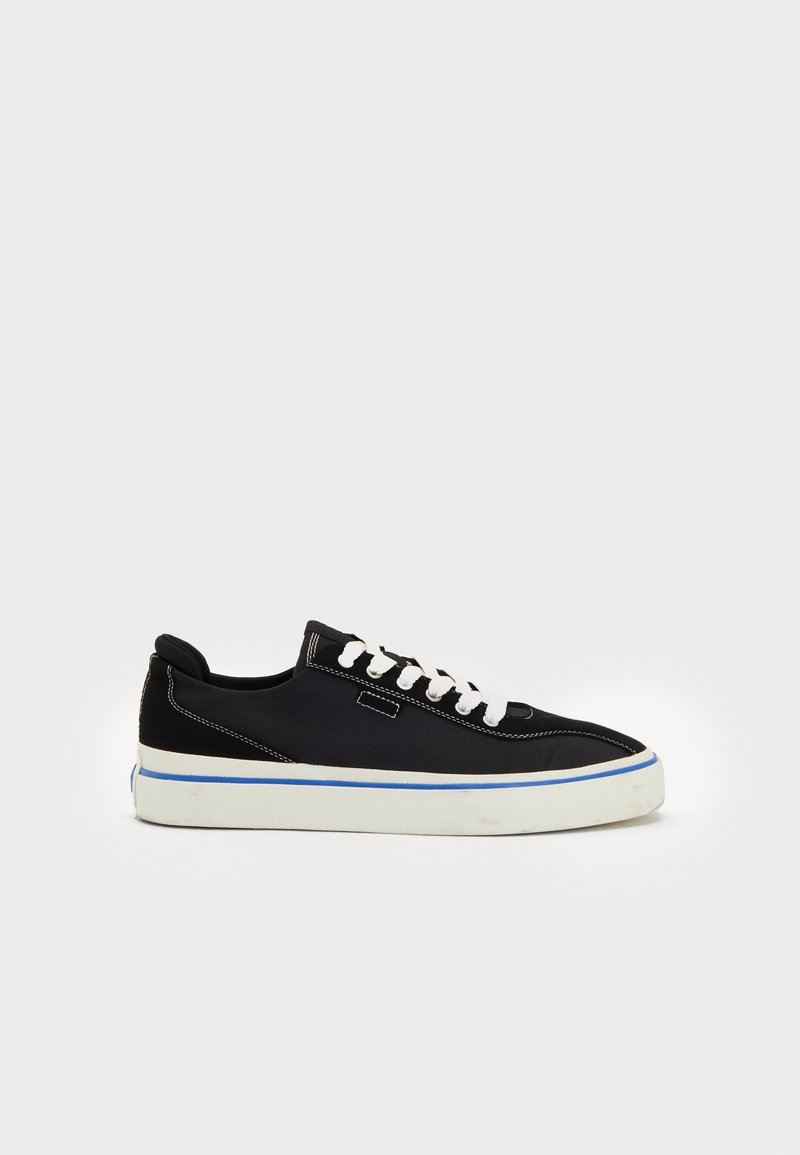 Svart canvas sneakers med vita snören, kontrasterande sömmar och en vit gummisula som accentueras av en blå linje. Lågt modell, slät yta.