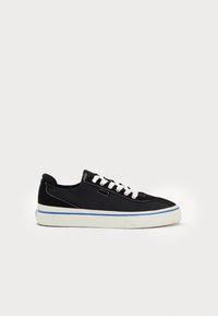 Black canvas sneakers with white laces, white sole and blue accent. Features smooth texture and rounded toe design. Contrast stitching visible.