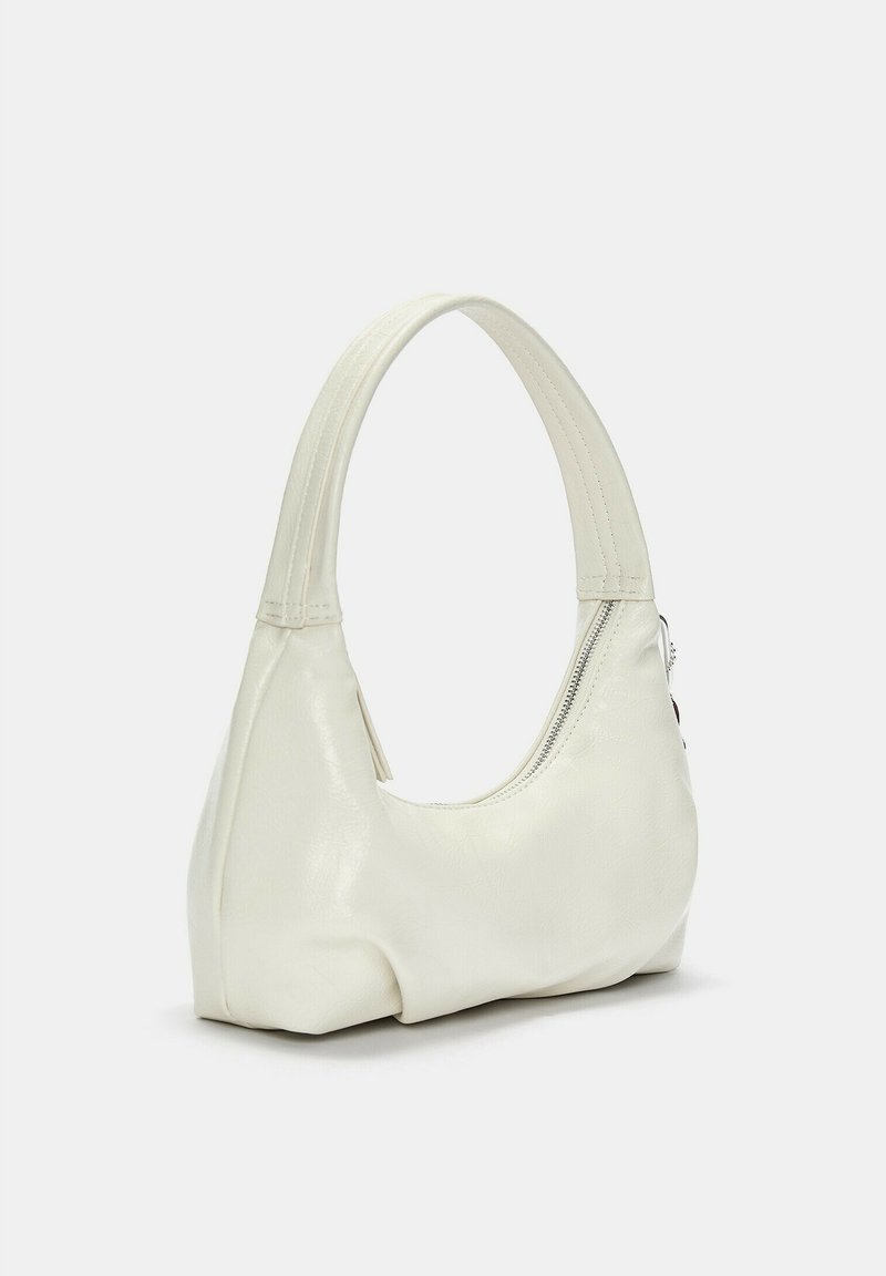 Bolso de piel blanca con un asa curva, cierre con cremallera y textura suave. Forma compacta con detalles de diseño minimalista.