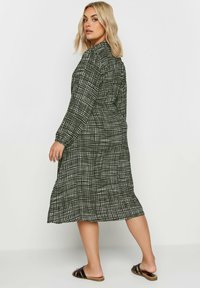 Svartvit mönstrad lång klänning med långa ärmar och en avslappnad passform, med en medellång nederkant och enkel knappdetalj bak.