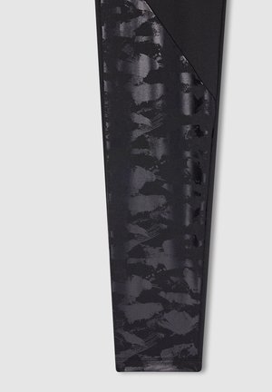 Leggings neri con un motivo astratto testurizzato in diverse sfumature di nero. Tessuto liscio con un design aderente e cuciture piatte.