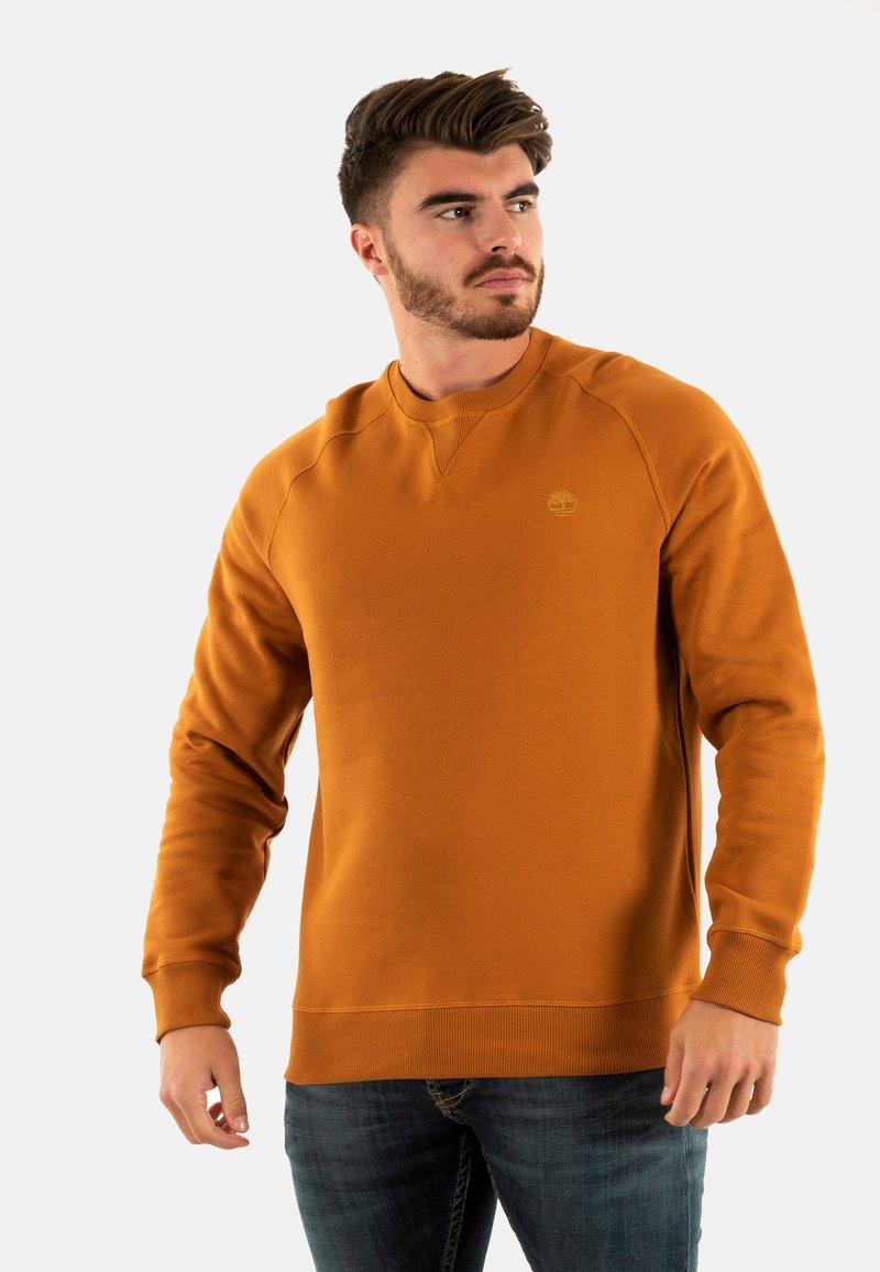 Sudadera de cuello redondo en color ámbar con puños y dobladillo de canalé. Presenta un logo en el pecho. Fabricada con un tejido suave y de textura lisa.