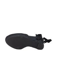 Zapato negro tipo slip-on con parte superior de tela texturizada, suela de goma y tacón plano. Presenta un acento de lazo en el talón y un patrón de suela acanalada.