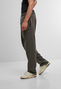 Mørkegrå joggere lavet af blødt stof med elastisk talje, sidelommer og et broderet logo på venstre lår.