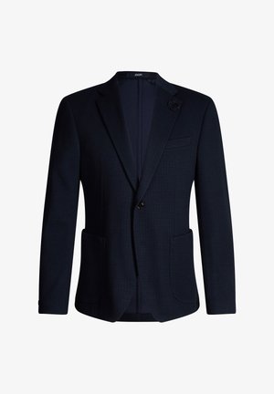 Granatowa marynarka męska z klapami z wycięciem, zapinana na jeden guzik, z dwoma naszywanymi kieszeniami z przodu, kieszenią na piersi oraz ozdobną broszką w kształcie kwiatu na klapie.