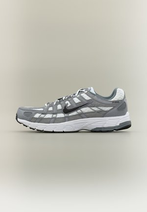 Γκρι και λευκό αθλητικό παπούτσι Nike P-6000 με μαύρο σήμα swoosh, επάνω μέρος από δίχτυ και σουέντ, και λευκή μαξιλαρωμένη σόλα, εμφανιζόμενο από το πλάι.