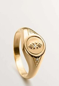 Anillo de oro con un diseño central redondeado que presenta un patrón de diamantes y pequeñas piedras preciosas. Acabado suave, banda cónica con detalles de acento.