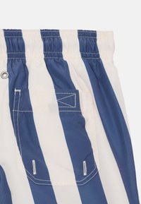 Los bañadores a rayas azules y blancas cuentan con una cinturilla elástica, un bolsillo trasero y una textura de tejido ligero y suave.