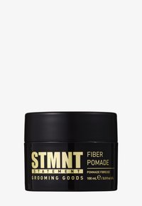 Bocal rond noir avec une finition lisse, étiqueté "STMNT FIBER POMADE" en lettres jaunes en gras. Contient 100 mL de produit.