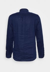 Marinblå linne skjorta med ståkrage, långärmade och knäppning i ärmslut, med en något skrynklig textur och en veckdetalj på baksidan.