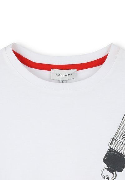 T-shirt bianco con colletto rotondo rosso e una grafica nera che presenta una borsa e una tracolla. Il tessuto sembra morbido e liscio.