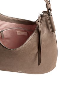 Beżowa torebka z zamszu z gładkimi skórzanymi wykończeniami. Posiada kieszeń zapinaną na zamek oraz miękką różową podszewkę. Zawiera odpinany pasek.