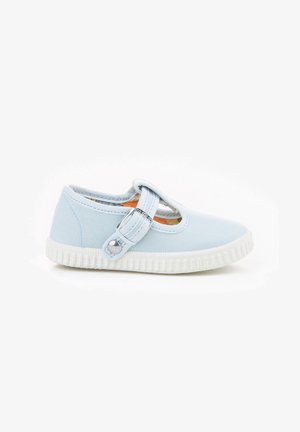 Zapato de lona azul claro con punta redondeada, correa cruzando el empeine y suela de goma blanca. Presenta un acento decorativo de botón en la correa.