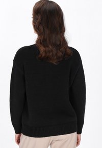 Maglione nero oversized con collo alto, lavorazione a maglia testurizzata, orlo a coste e maniche lunghe, caratterizzato da una vestibilità rilassata e senza decorazioni visibili.
