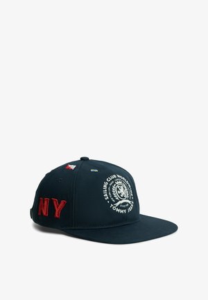 Marineblauwe baseballpet met rood geborduurd "NY", nautische vlaggen en wit rond Tommy Jeans Sailing Club-logo op het voorpaneel.