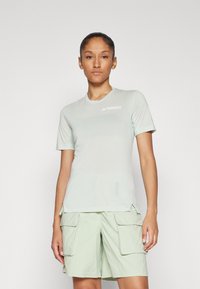 Lys grønn kortermet T-skjorte laget av lettvektig stoff, med rund hals og TERREX-logo, kombinert med matchende cargo-shorts.