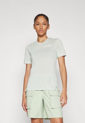 Hellgrünes Kurzarm-T-Shirt aus leichtem Material mit Rundhalsausschnitt und TERREX-Logo, kombiniert mit passenden Cargo-Shorts.