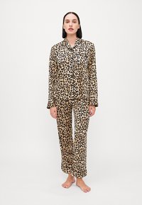 Pajama set s leopard uzorkom u boji pješčenjaka i crne, s dugim rukavima i dugim majicom na dugme s džepom te slobodnim hlačama. Glatka tkanina.