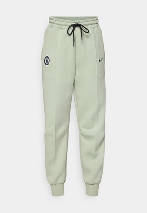 Pantaloni da jogging Nike di colore verde chiaro con vita elastica, stringhe, tasche laterali e logo del Chelsea FC sulla coscia sinistra.