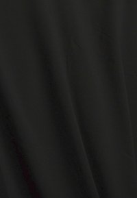 Tissu noir uni avec des plis doux créant des ombres délicates et une texture.