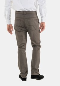 Pantalones de algodón marrones con un diseño de pierna recta, que cuentan con dos bolsillos traseros y detalles de costura visibles. Llevados con zapatos negros.