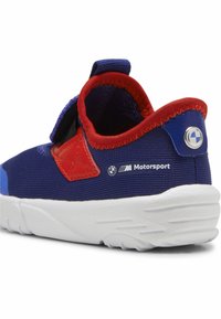 Sininen ja punainen urheilukenkä, jossa on teksturoitu päällinen, säädettävä tarranauha ja valkoinen kumipohja. Varustettu BMW Motorsport -brändillä.