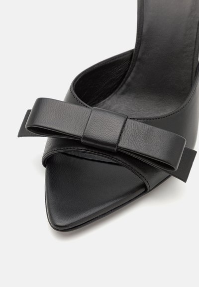Sort læder højhælede sko med spids tå og bred sløjfedetalje. Glat tekstur med åben design på siderne, elegant og str�ømlinet form.