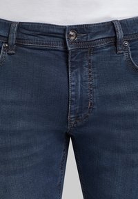 Mörkblå denimjeans med knappstängning, femficksdesign och kontrasterande sömmar. Tyget har en lätt urtvättad yta.