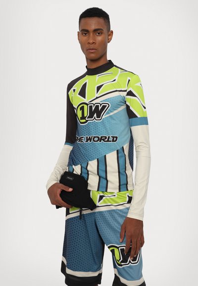 Long-sleeve, patterned athletic shirt in black, green, and blue, paired with matching shorts. Features graphics and contrasting accents.