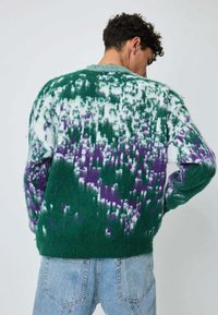 Pull surdimensionn�é vert en tricot avec un motif dégradé de violet et blanc. Texture douce et col ras du cou, vue de dos.