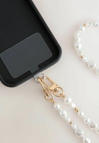 Husa de telefon neagră cu un suport sigur; dispune de o curea de perlă detașabilă cu accente aurii și un slot transparent pentru card pe spate.