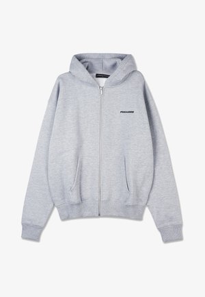 Felpa grigia con zip realizzata in morbido tessuto a boucle. Presenta una tasca a marsupio e polsini a costine. Sul fronte c'è un piccolo logo nero sul lato sinistro del petto.