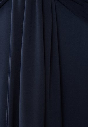 Marineblå stof hænger elegant med en blød tekstur og bløde folder. Materialet ser let og svævende ud med en glat afslutning.