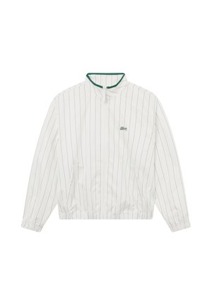 Weiße Jacke mit Reißverschluss und dünnen vertikalen schwarzen Streifen, grün akzentuierter Kragen, elastische Bündchen und kleines schwarzes Logo auf der Brust.
