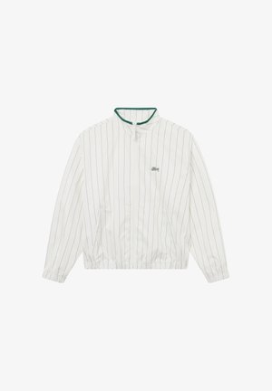 Hvit jakke med glidelås og tynne, vertikale svarte striper, krage med grønn kant, elastiske mansjetter og liten svart logo på brystet.