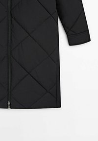 Zwarte doorgestikte pufferjas met een ritssluiting over de volledige lengte, diagonale stikpatronen en lange mouwen. Zacht, geïsoleerd materiaal.