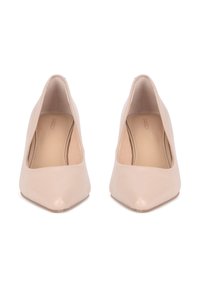 Zapatos de salón de tacón alto en cuero color nude con punta puntiaguda, textura lisa y diseño de empeine bajo. La plantilla interior es de color beige.