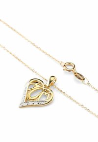 Auksinis širdies formos pakabutis su „MOM“ išpjova, puoštas skaidriais brangakmeniais, ant subtilaus grandinėlės su vėžlio tipo užsegimu.