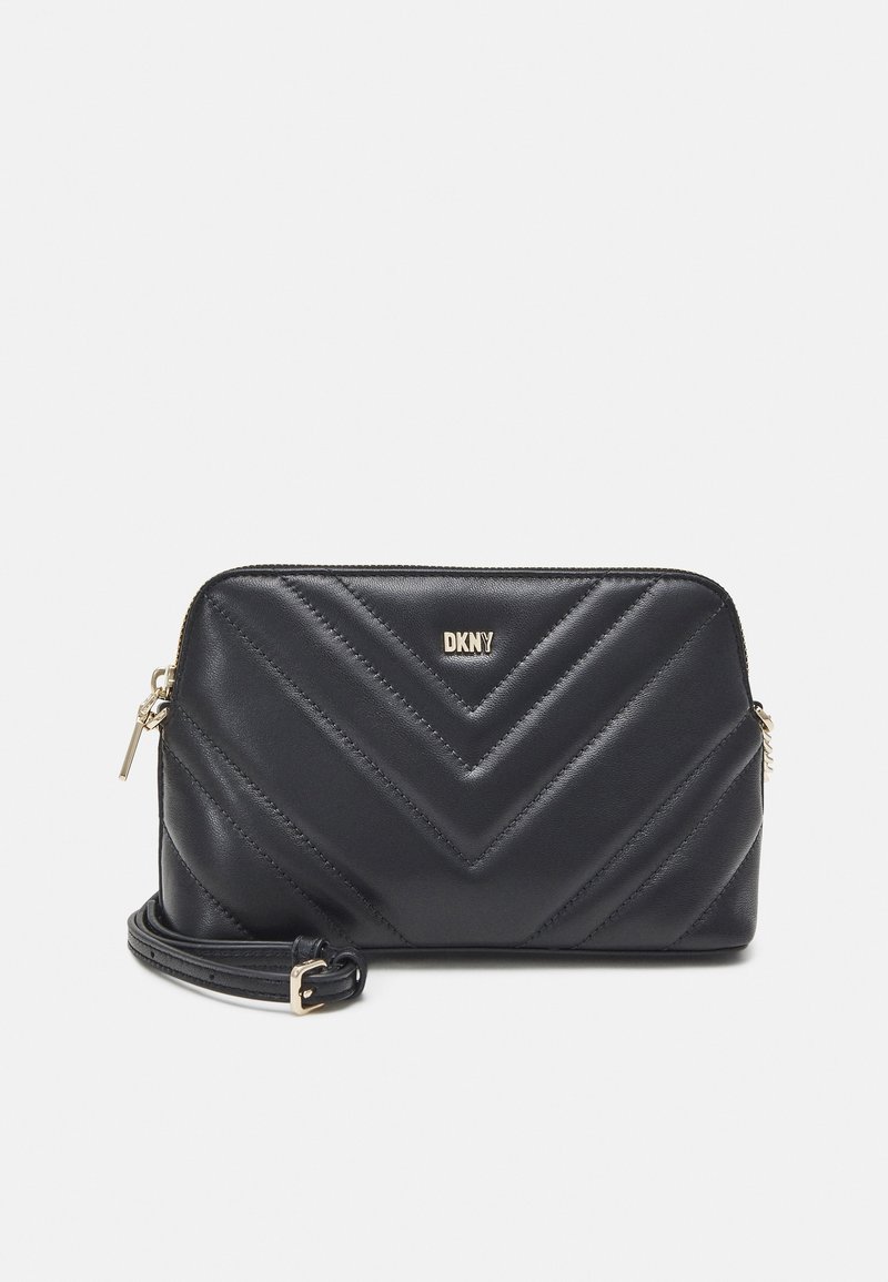 Sac bandoulière en cuir matelassé noir DKNY avec fermeture éclair dorée et bandoulière réglable sur fond uni.