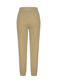 Pantalon de jogging beige avec une taille élastique, coupe fuselée et des poignets élastiques aux chevilles. Texture de tissu lisse avec une couleur unie.
