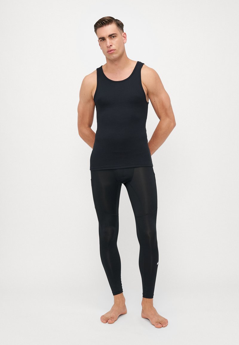 Schwarzes Baumwoll-Top mit schwarzer, eng anliegender Leggings, hergestellt aus einem glatten, dehnbaren Material. Hat einen runden Ausschnitt und keine sichtbaren Logos.