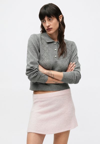 Sivý pletený sveter s golierovým výstrihom, diamantovým vzorom a perlami na gombíkoch, kombinovaný s svetloružovou, útulnou mini sukňou.