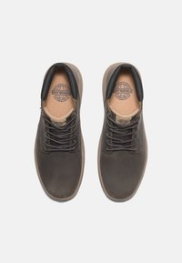 Braune Leder Schuhe mit glatter Textur, runder Zehenform, Schnürsenkeln und einem weichen schwarzen Kragen. Das Innere ist mit einem beigen Futter und Branding ausgestattet.