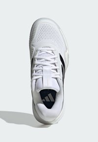 Bílá sportovní bota s síťovaným svrškem, černými akcenty, polstrovaným límcem a gumovou podrážkou. Má šněrování a logo na jazyku.