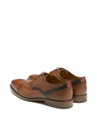 Chaussures de ville en cuir marron avec une finition lisse, bout rond et accents noirs contrastants sur les côtés. Semelle en caoutchouc plate et design à lacets.