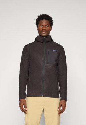 Black fleece jacket with a textured pattern, high neck, and zipper closure. Features a chest pocket and side pockets for utility.